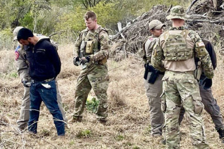 Military personnel detaining a migrant as part of Texas' infamous Operation Lone Star