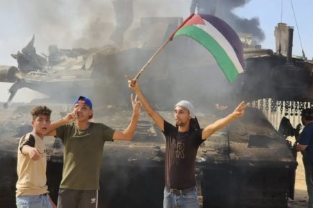 Hamas’ armed wing, the Izz ad-Din al-Qassam Brigades hold a Palestinian flag as they destroy a tank of Israeli forces in Gaza City, Gaza on 07 October 2023. Photo: Hani Alshaer – Anadolu Agency