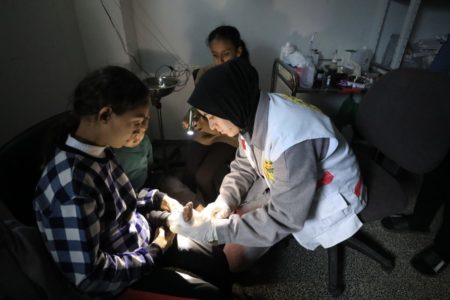A child in Gaza is attended in a hospital with only the light of a flashlight. Photo: WHO