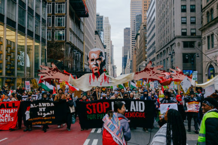 Protesters march down Fifth Avenue in Manhattan, NYC with a puppet of Joe Biden