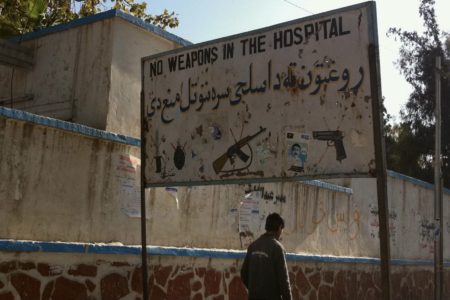 Man walking in front of a hospital sign in Afghanistan. Photo: Peretz Partensky / Wikimedia Commons