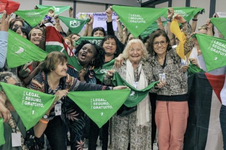 Participants in the 5th People's Health Assembly raise the green scarf symbolizing the struggle for abortion access in Latin America. Photo: People's Health Movement