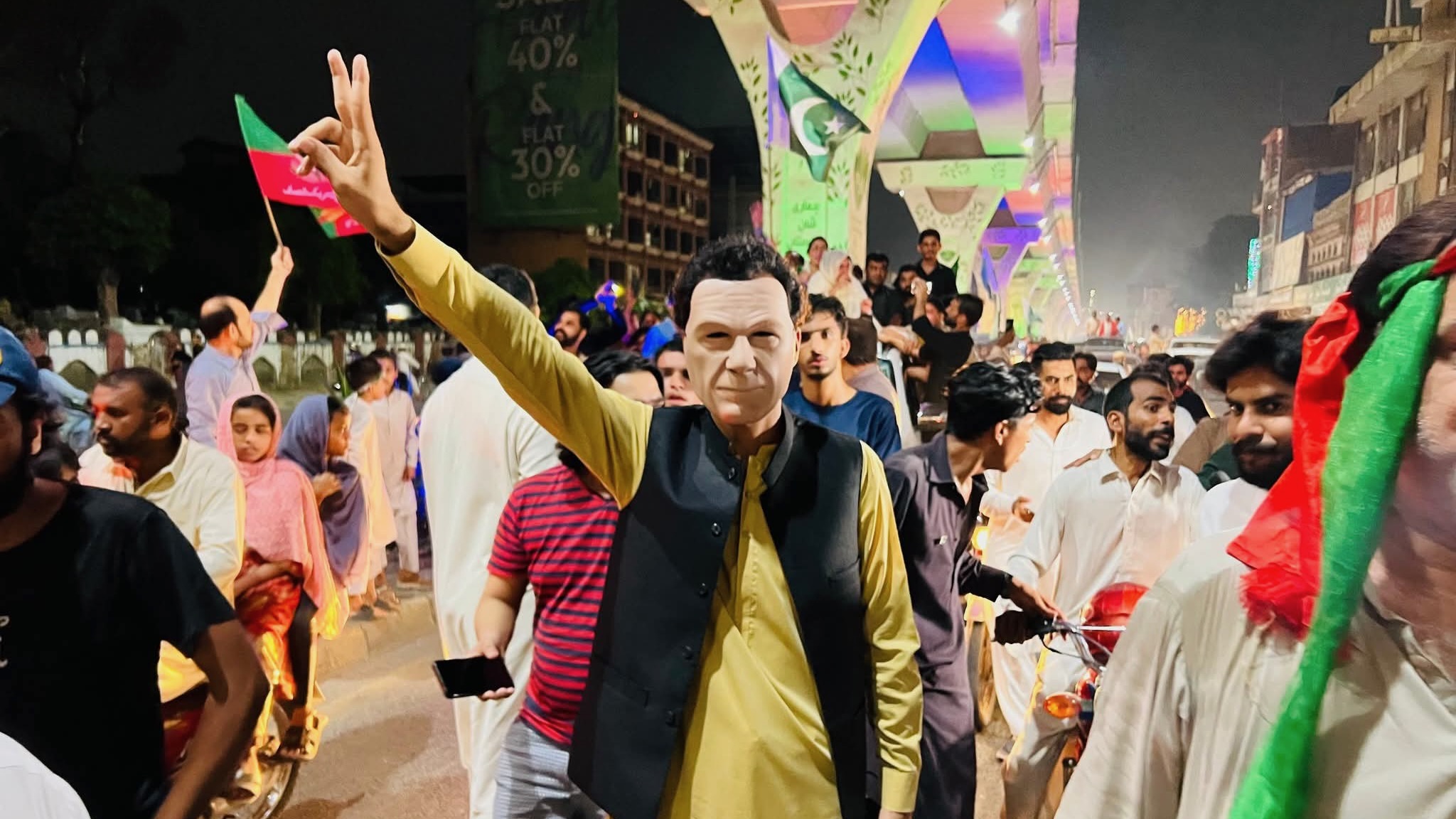 Man wearing a mask holds up two fingers during a protest