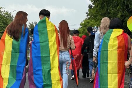 Beating back Bukele’s war on gender ideology people marching with rainbow flags draped over themselves