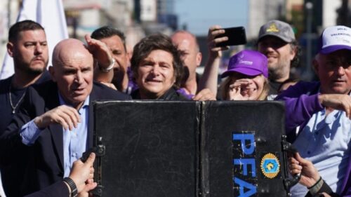 Security and staff hold a suitcase up in front of Argentine President Milei