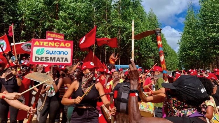 Protestors in Brazil dance and make music holding farm tools and raising placards against corporate land ownership