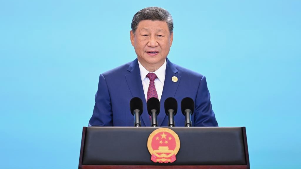 Chinese president speaks at podium in front of blue wall