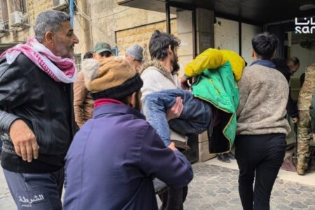 People carrying injured man after fighting between government forces and SDF An injured man is carried off by several people in Syria's Aleppo