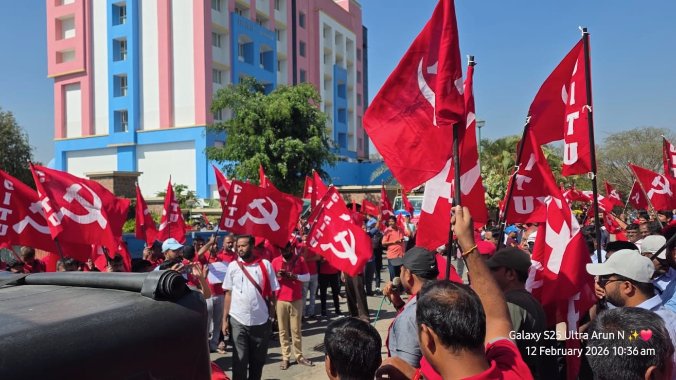 Indian people hold red hammer and sickle flags outside building