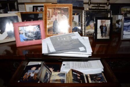 trump-epstein-photo Desk drawer with printed pictures including Trump with Epstein and Ghislaine Maxwell and Trump standing with women in swimwear.