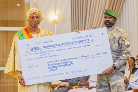 Colonel Assimi Goita distributes mining checks to vulnerable communities in Mali Malian woman and Assimi Goita hold up large check