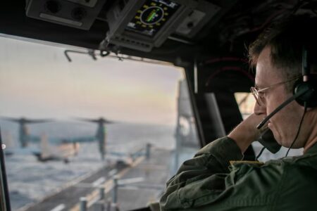 A naval officer aboard USS Tripoli oversees flight operations from the control tower as the amphibious assault ship sails in the Arabian Sea. A naval officer aboard USS Tripoli oversees flight operations from the control tower as the amphibious assault ship sails in the Arabian Sea.