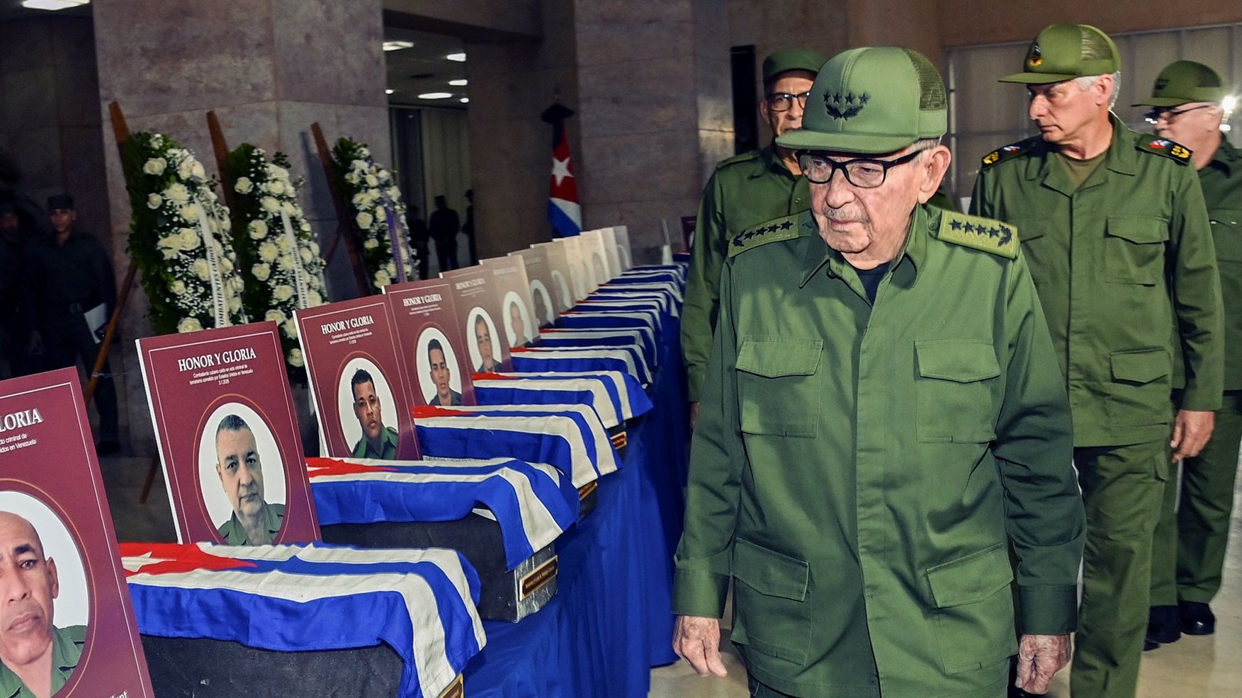 Raúl Castro walks in front of coffins with Cuban flags over them